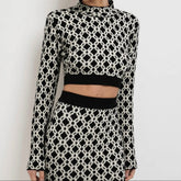 Person wearing a black and white patterned outfit on a plain background